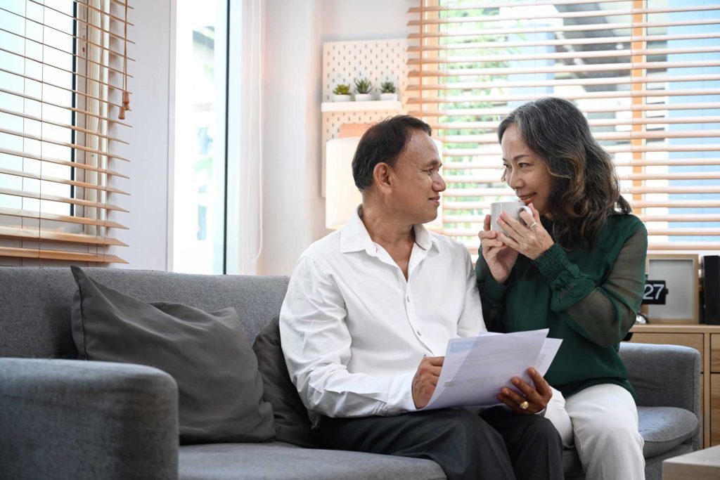 Senior couple sitting on a couch budgeting | Featured image for Blinds on a Budget Blog from U Blinds Australia.