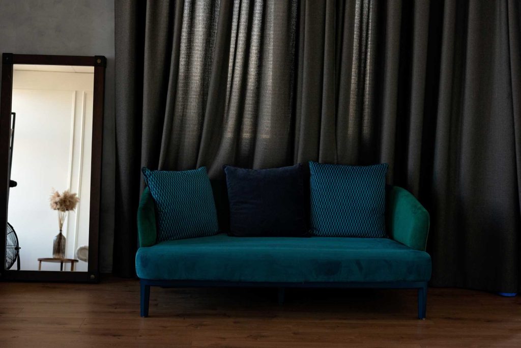 Modern blue couch against dark curtains | Featured image for the 2023 Curtain Trends Blog from U Blinds Australia.