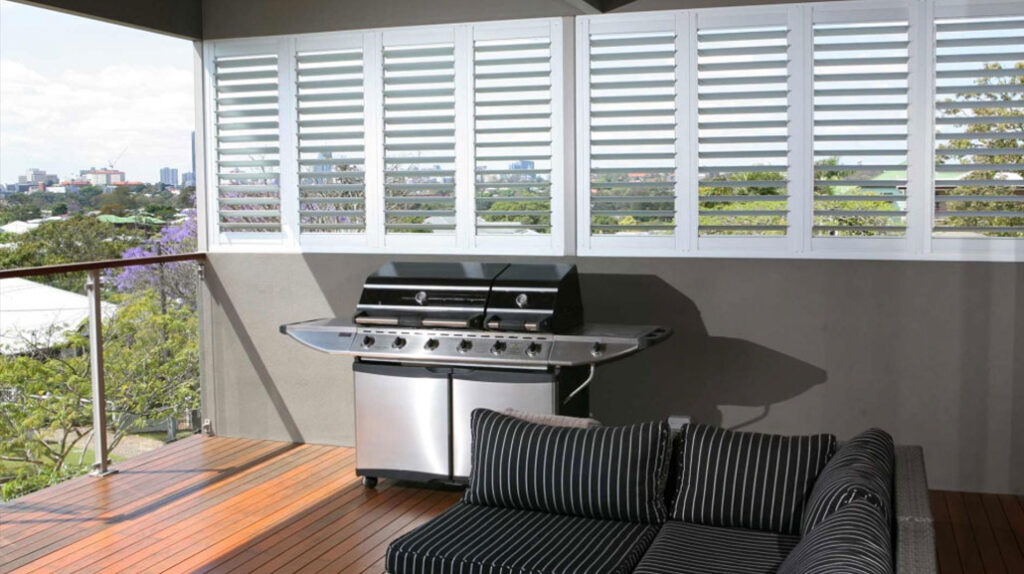 Patio with a barbeque, black sofa and white shutters | Featured image for the top level Shutters page for U Blinds Australia.