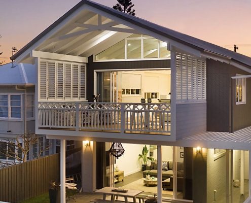 House at dusk with many lights glowing throw polymer plantation shutters | Featured Image for the PVC Plantation Shutters Page of U Blinds Australia.