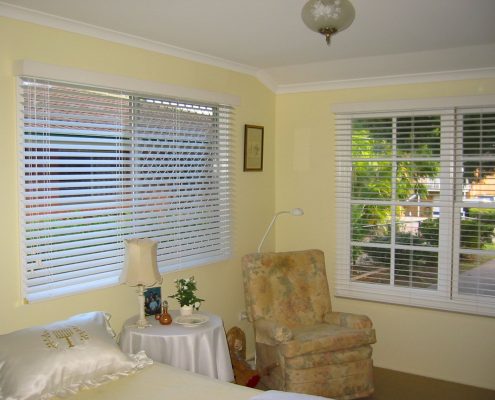 Blinds covering a window behind a chair | Featured Image for the Timber Venetian Blinds page of U Blinds Australia.